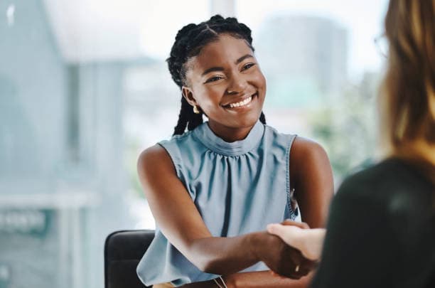 A smiling professional greeting another person during a business conversation.
